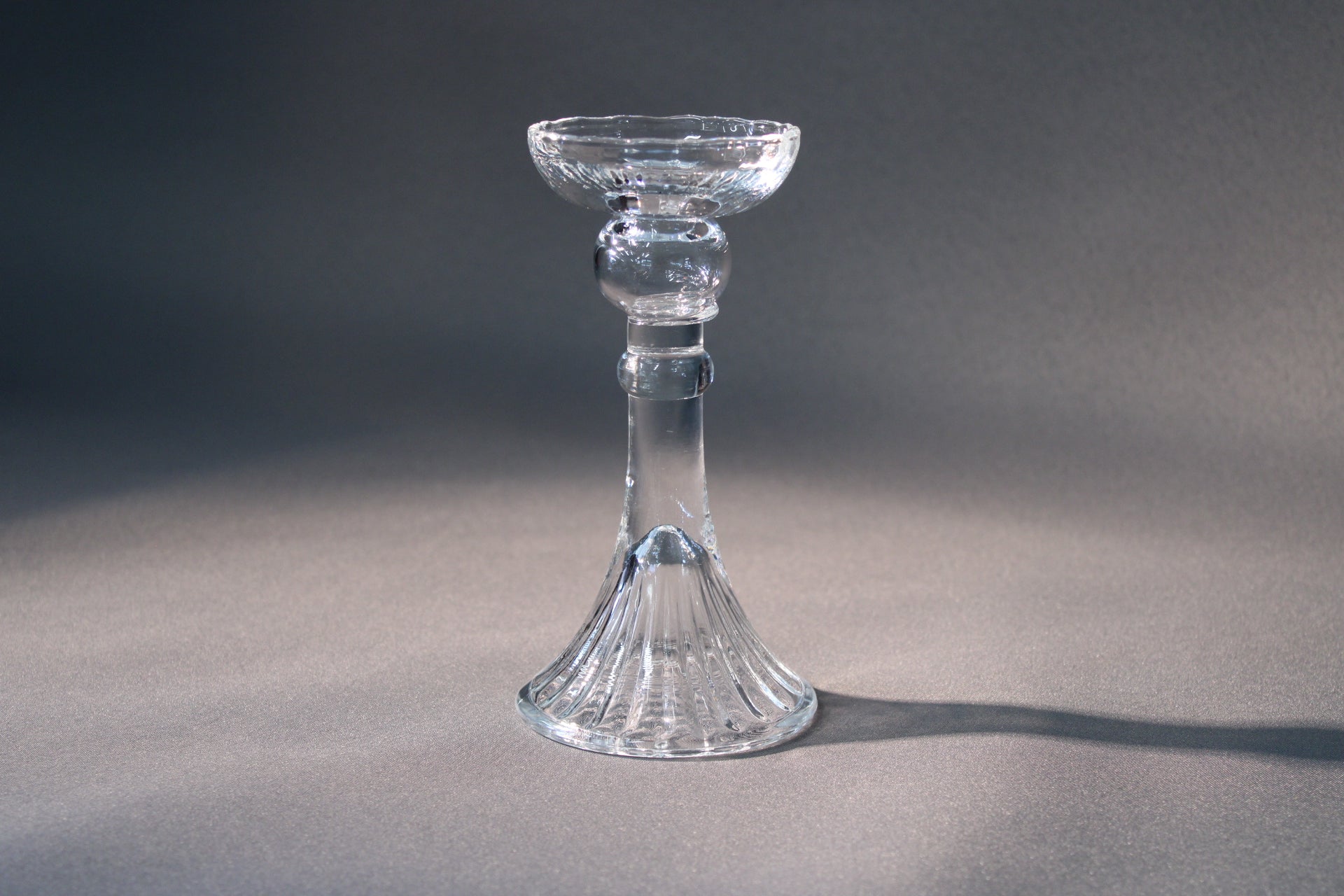 Nuutajärvi Romanssi kynttilänjalka. Kerttu Nurmisen suunnittelema kirkas lasijalka, joka tuo hillittyä eleganssia kattaukseen ja sisustukseen.