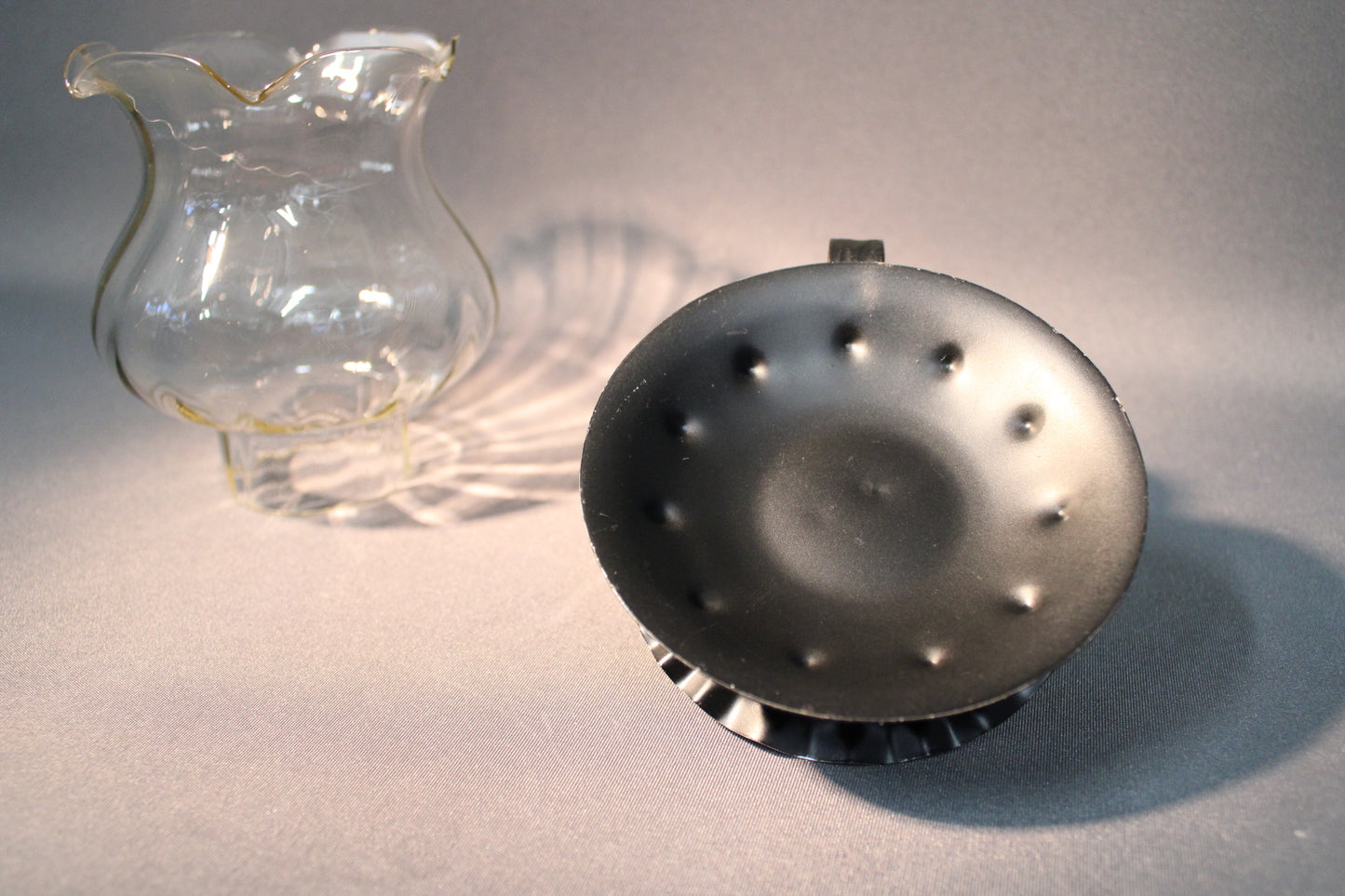 Lasinen kynttilälyhty ja musta metallijalka, pohjan yksityiskohta