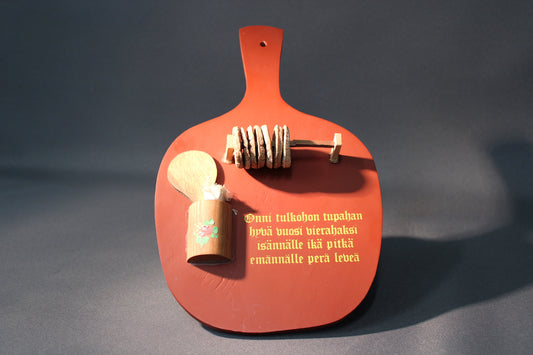 Puinen suomalainen vintage-toivotustaulu, jossa kansanomainen runo, lusikka ja rahakasa-symboli