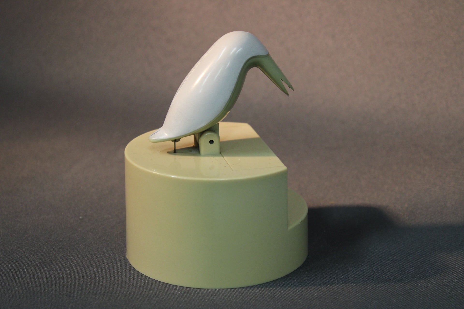 Hammastikkuannostelija sivulta kuvattuna, lintufiguuri kallistettuna.