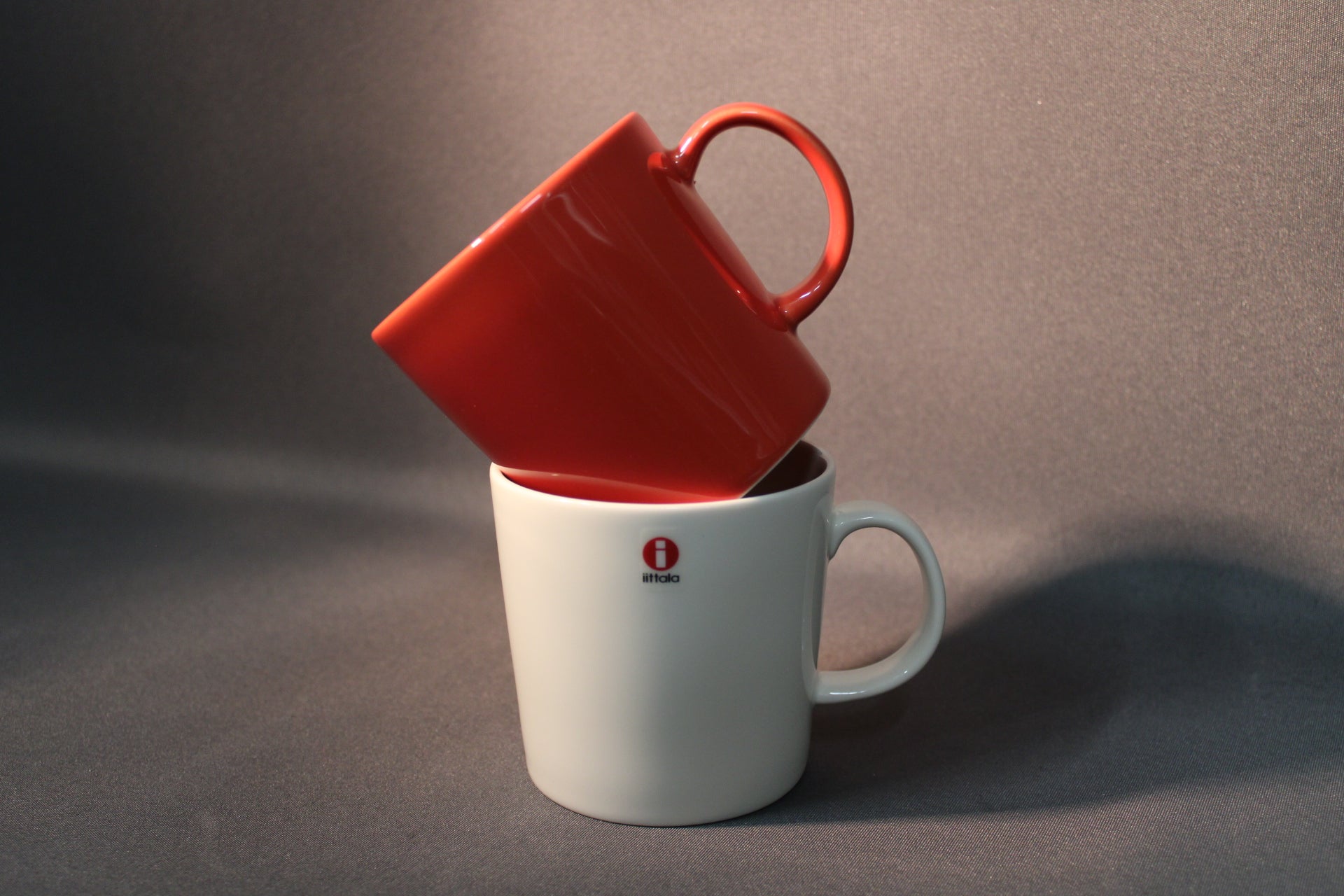 Iittala Teema -sarjan punainen muki nojaa valkoisen mukin sisään.