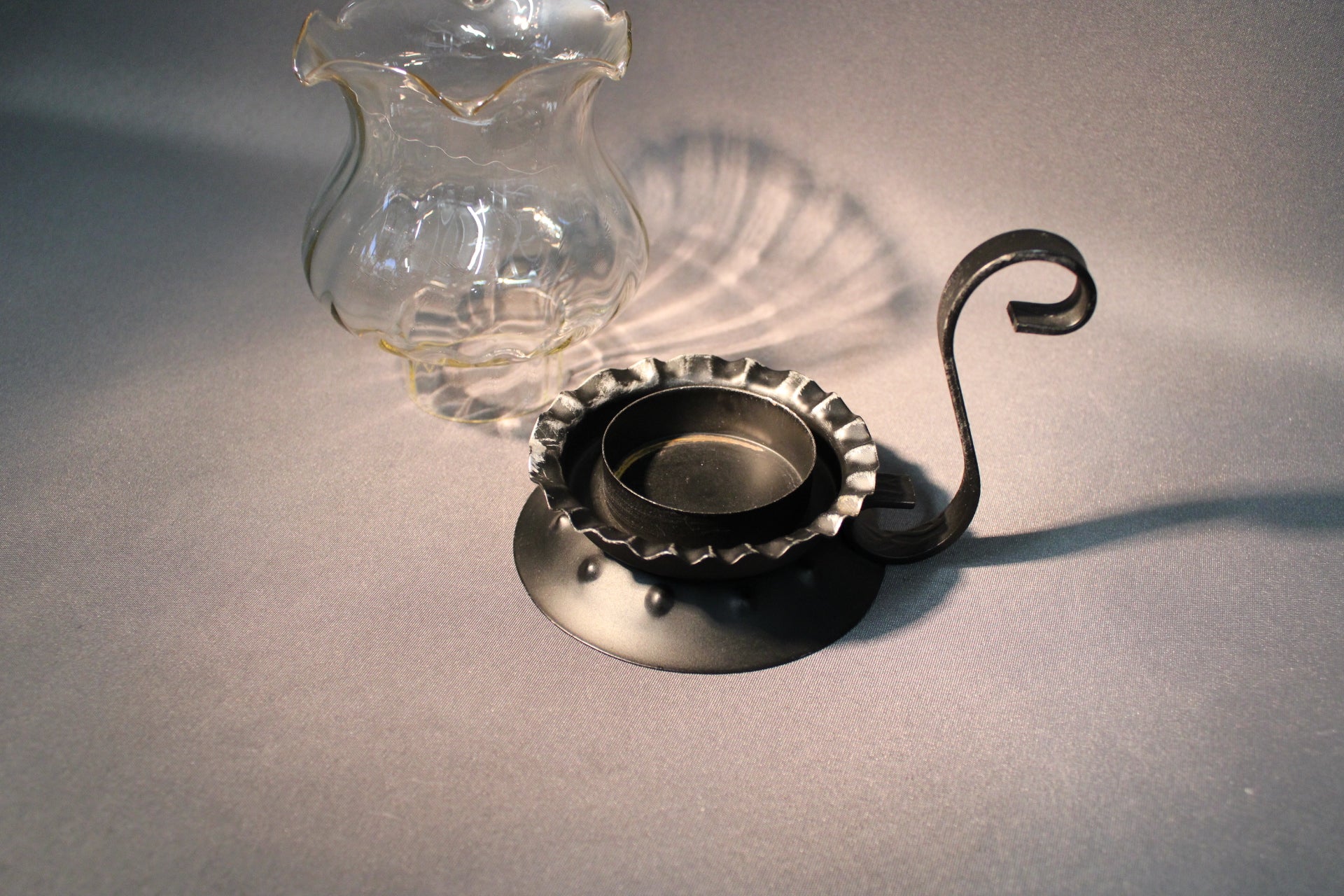Kynttilälyhdyn irrotettava lasiosa ja metallijalka, kirkas lasi ja musta metalli