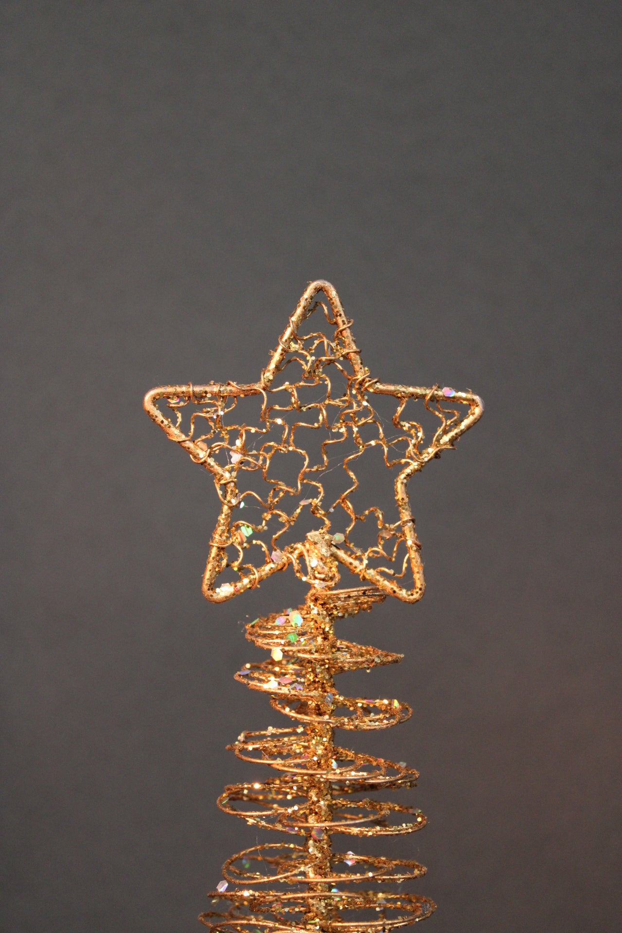 Metallisen koristekuusen tähtikoriste lähikuvassa, kultainen glitterpinta