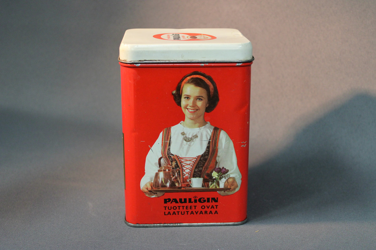 Pauligin vintage-peltipurkki punaisella pohjalla ja tarjoilijatar-kuvalla