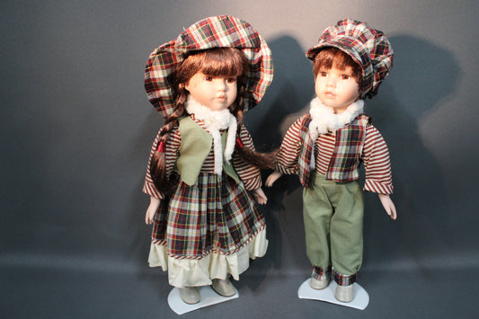 Kaksi posliininukkea, tyttö ja poika 40 cm, seisovat vierekkäin telineillä.