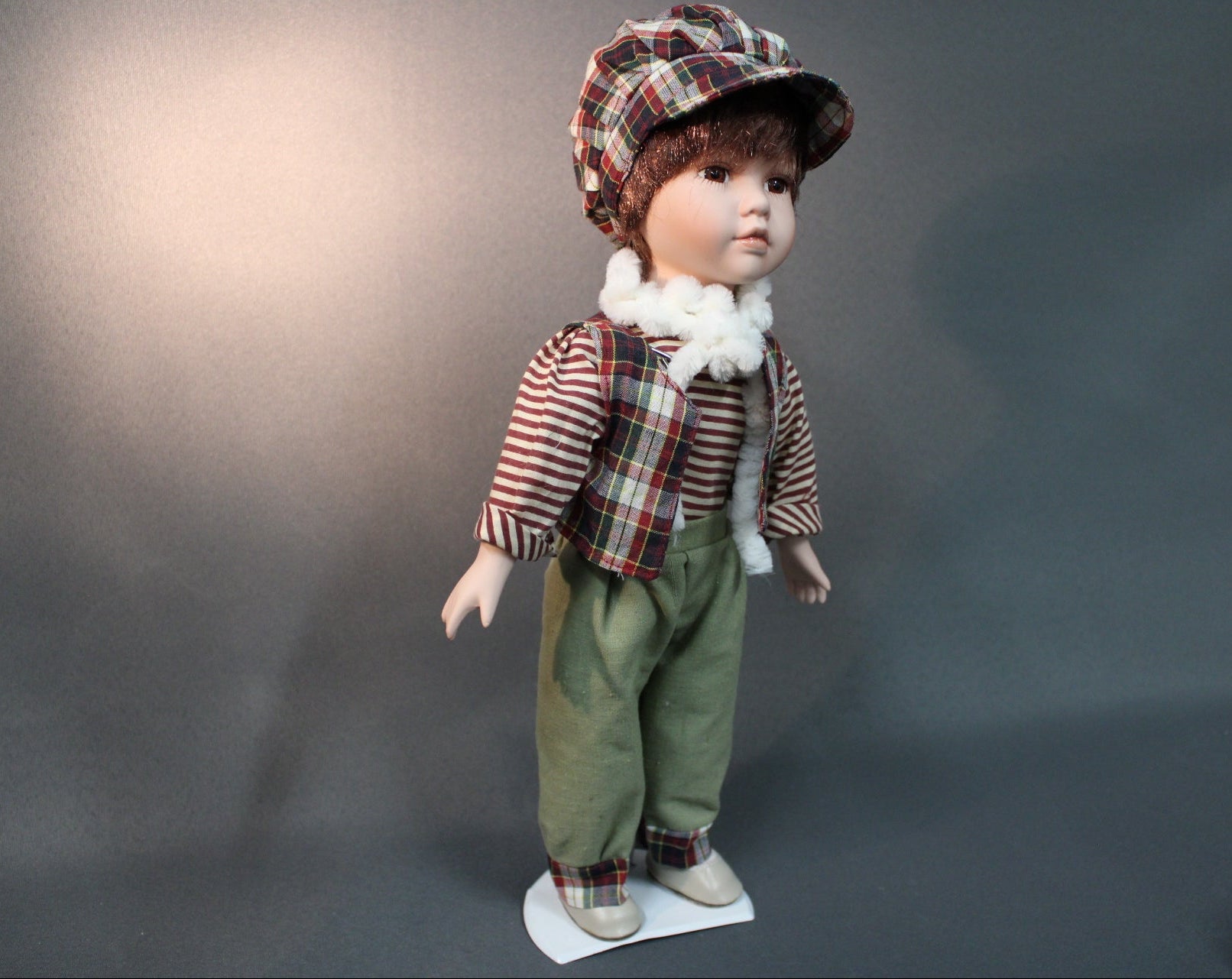 Posliininukke poika 40 cm edestä, vihreät housut ja ruutupäähine.