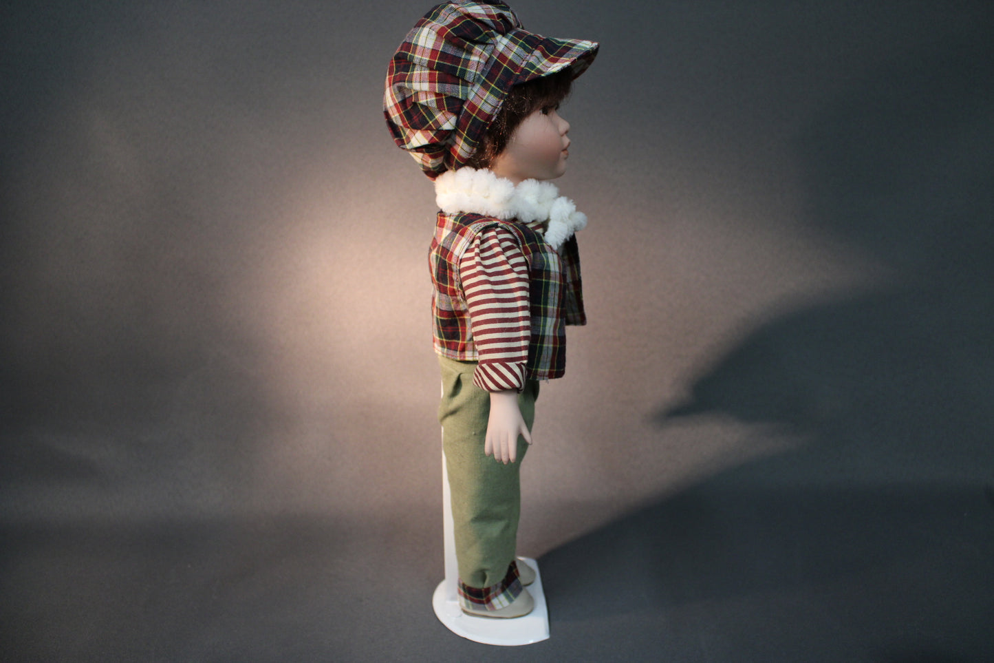 Posliininukke poika 40 cm sivukuvassa, raidallinen paita ja ruutuliivi.