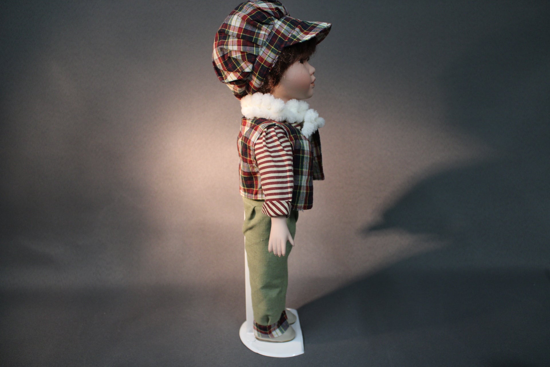 Posliininukke poika 40 cm sivukuvassa, raidallinen paita ja ruutuliivi.