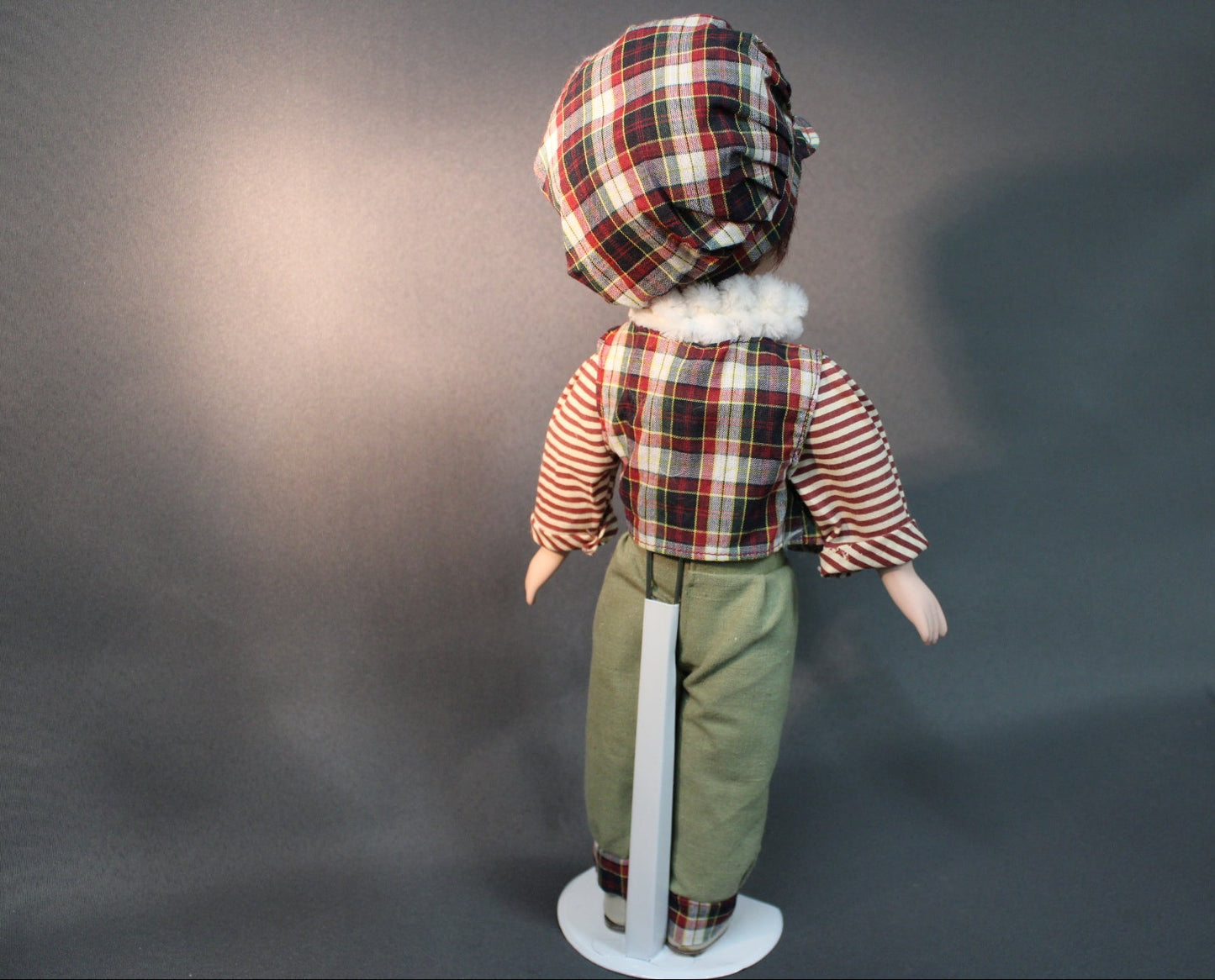 Posliininukke poika 40 cm kuvattuna takaa, ruutupäähine ja vihreät housut.
