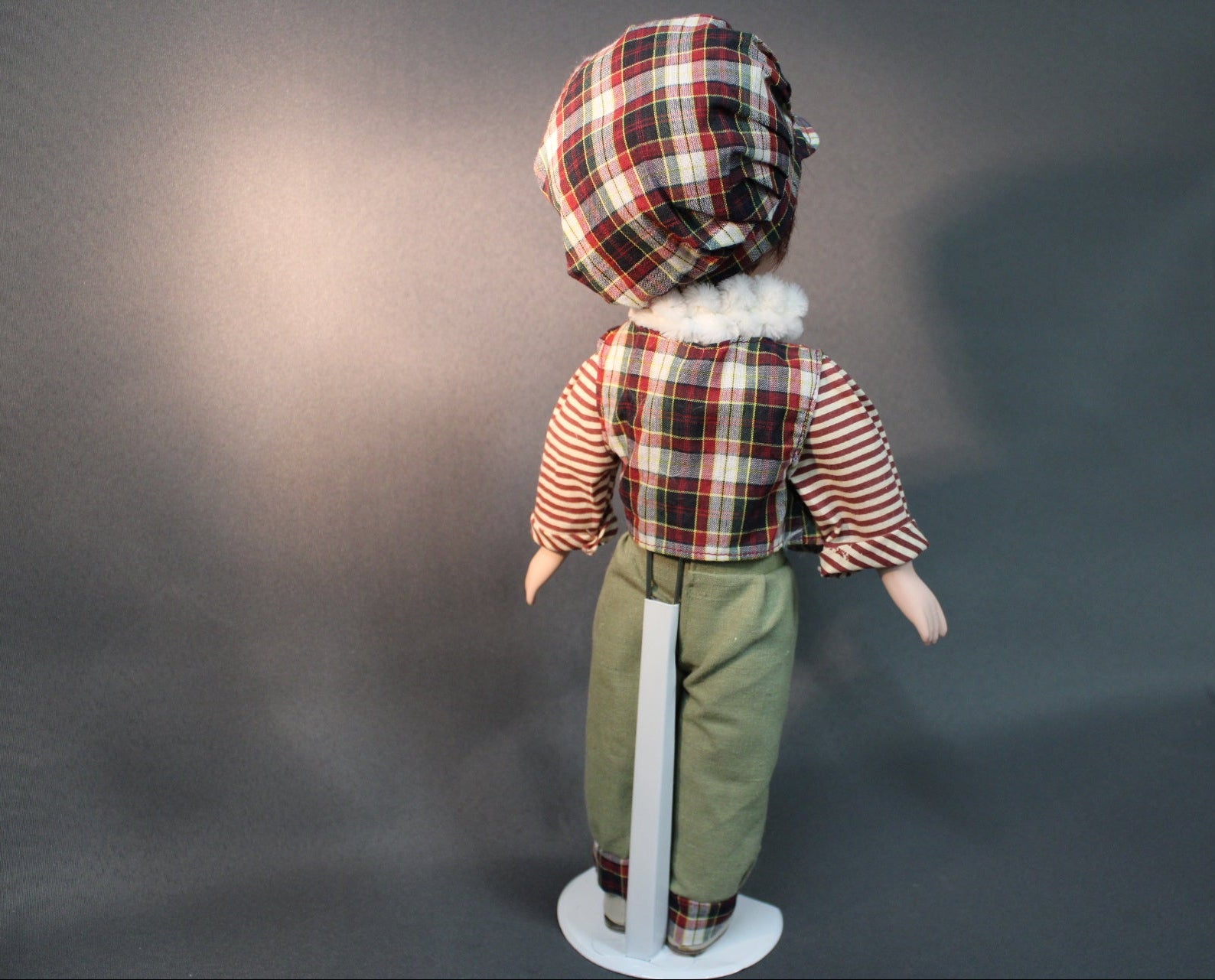 Posliininukke poika 40 cm kuvattuna takaa, ruutupäähine ja vihreät housut.