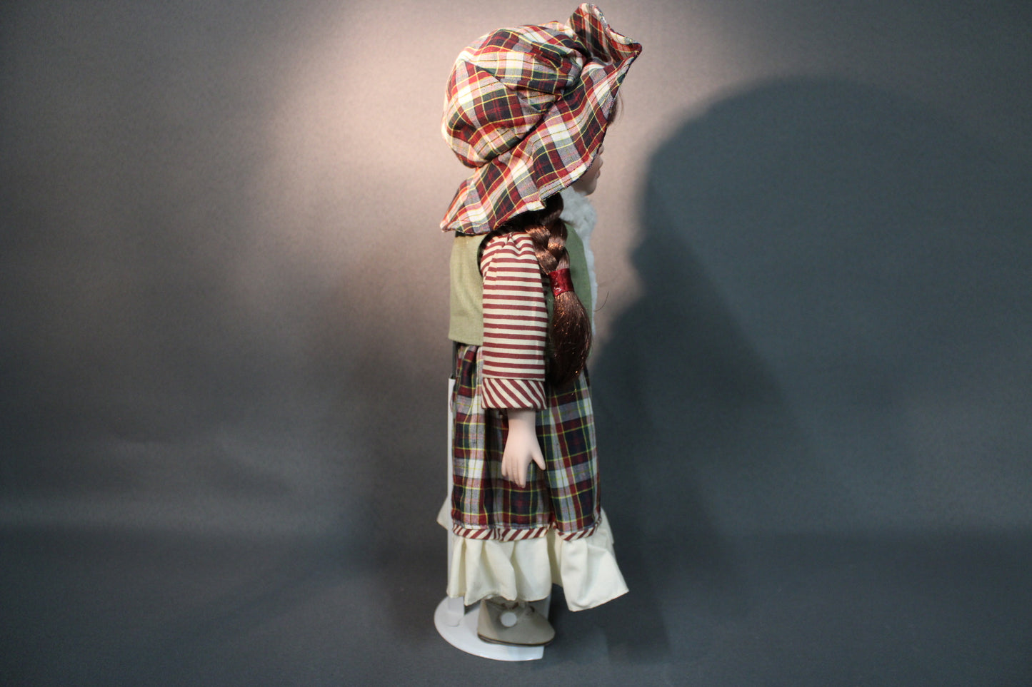 Posliininukke tyttö 40 cm sivukuvassa, ruskeat letit ja ruutupuku.