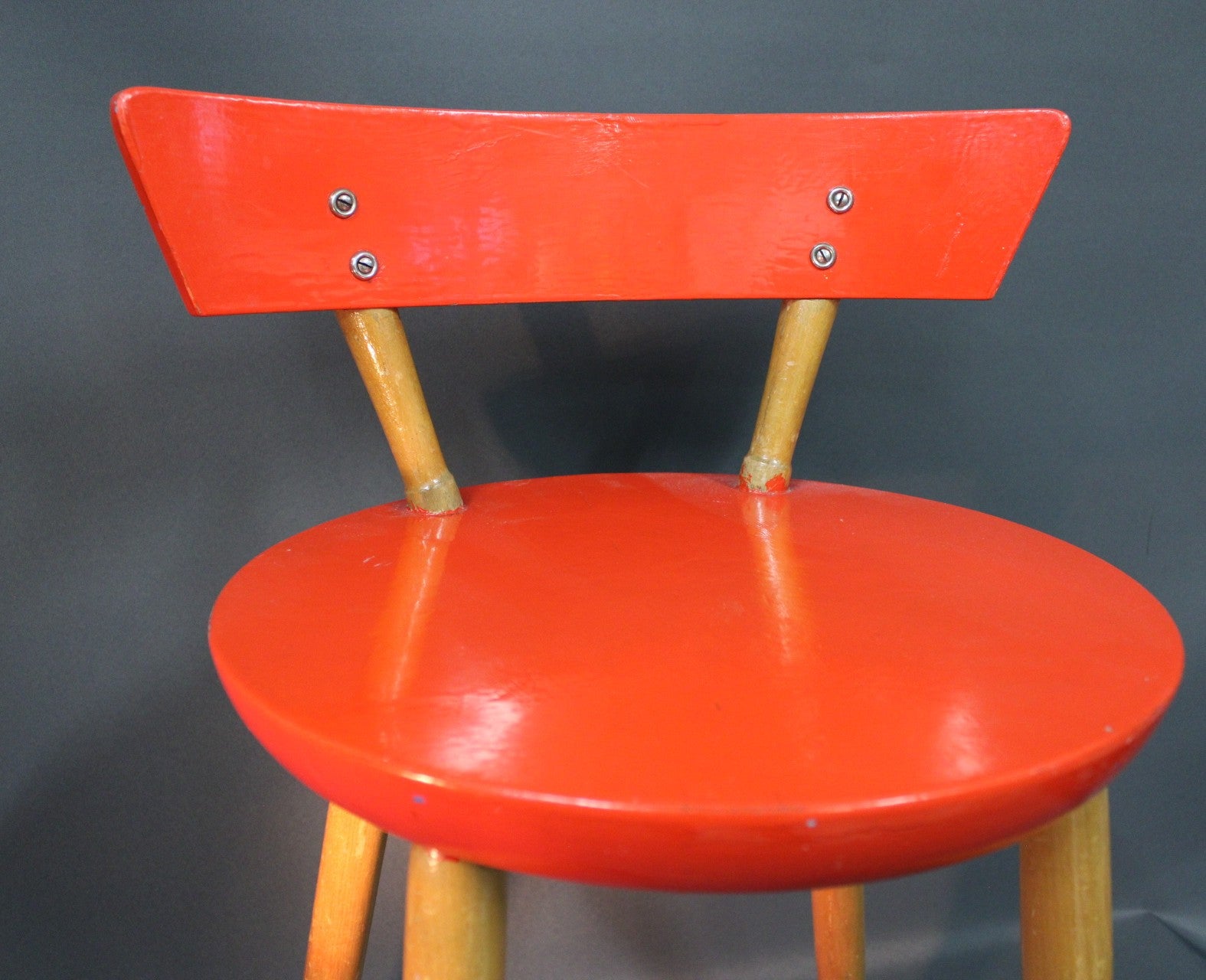 Puinen 1950-luvun tuoli, punainen istuin ja selkänoja, vaaleat puujalat, istuinosa