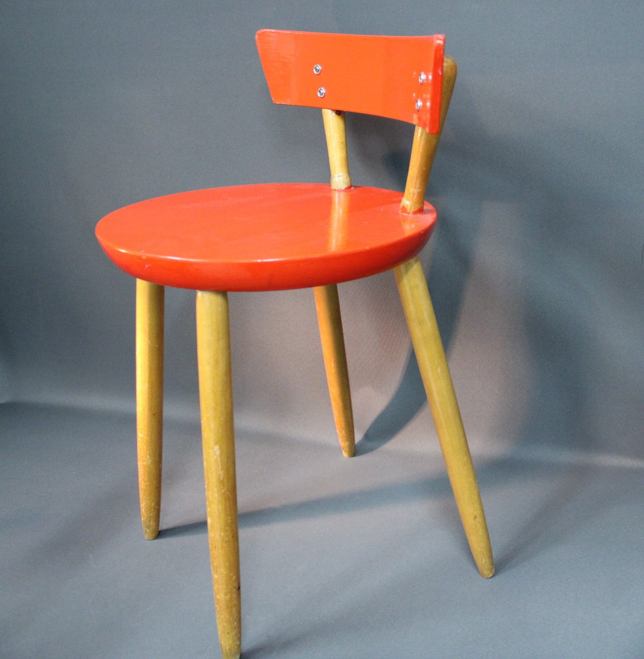 Puinen 1950-luvun tuoli, punainen istuin ja selkänoja, vaaleat puujalat, sivusta