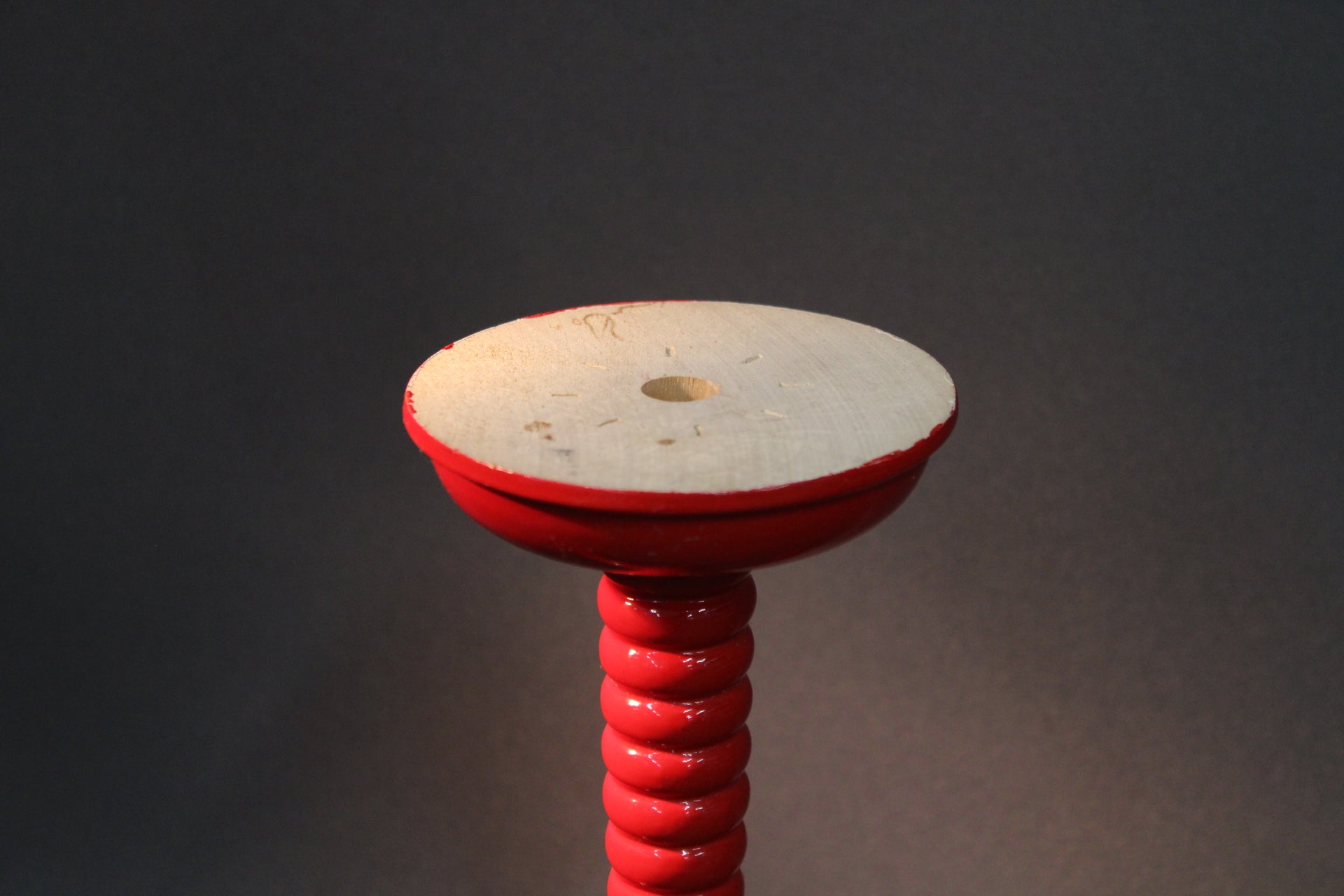 Punainen puinen kynttilänjalka ylhäältä kuvattuna, kolmihaarainen suomalainen puutyö