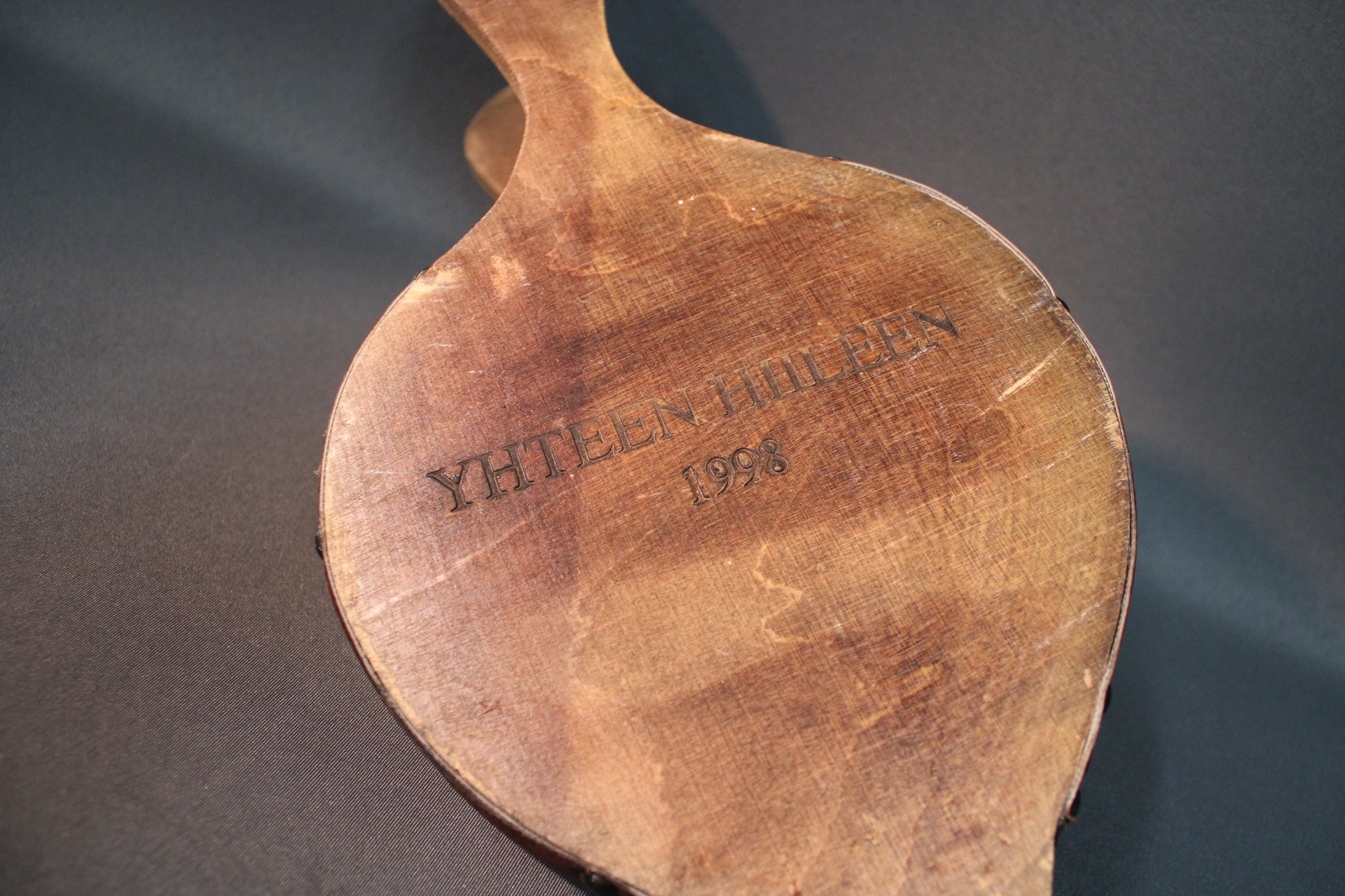 Takkapalkeen takapuoli, poltettu teksti Yhteen hiileen 1998, puinen pinta