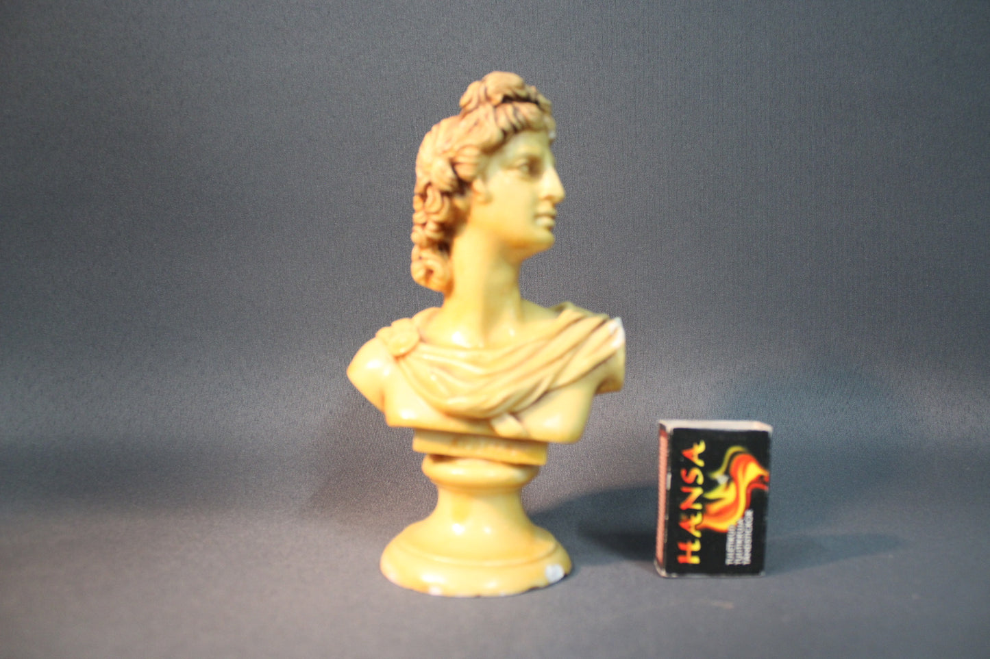 Klassinen rintakuva vaalea keltainen patsas, kokovertailu tulitikkurasian kanssa