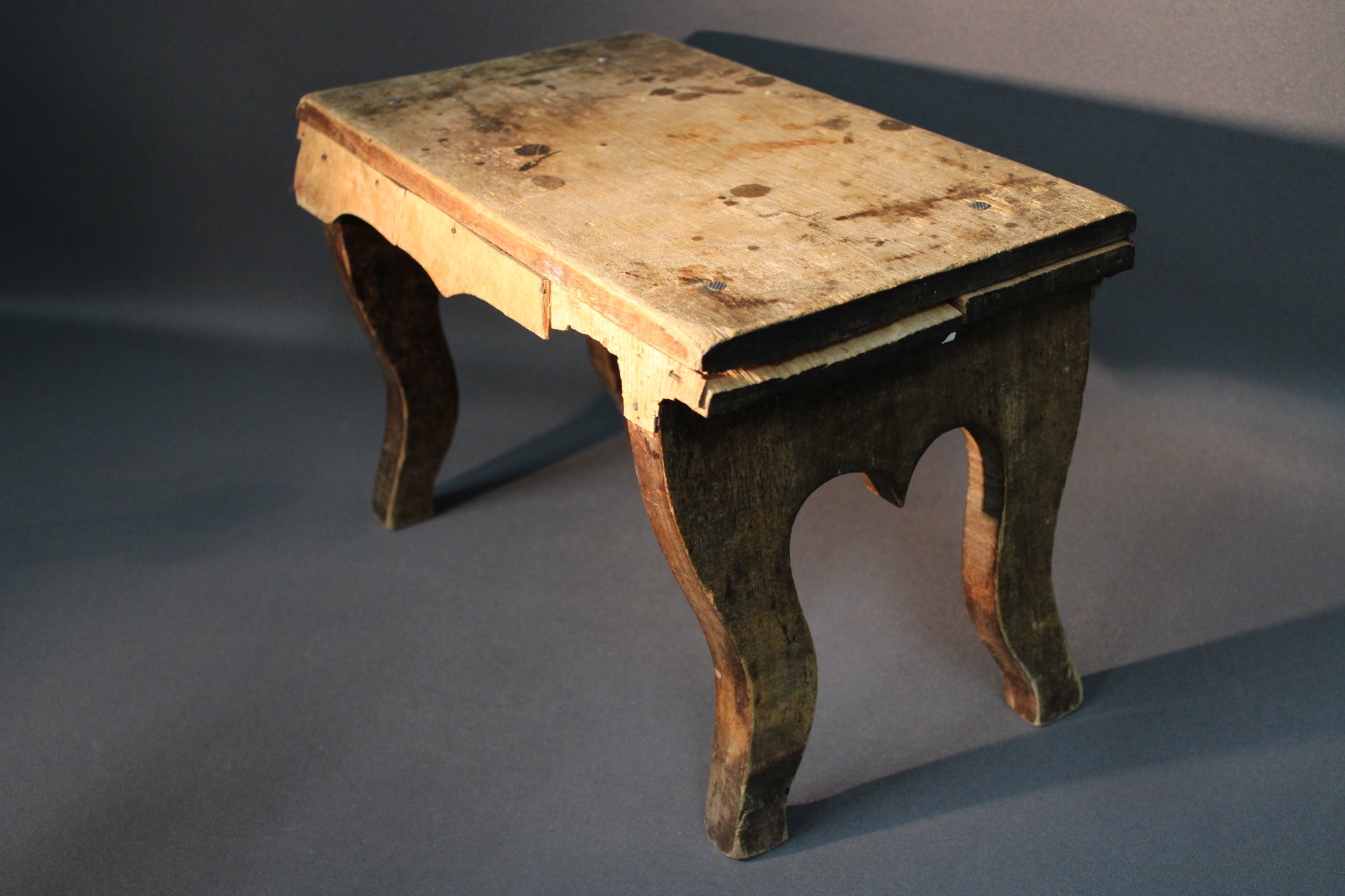 Vanha puinen jakkara ylhäältä kuvattuna, kulunut puupinta ja naarmuja