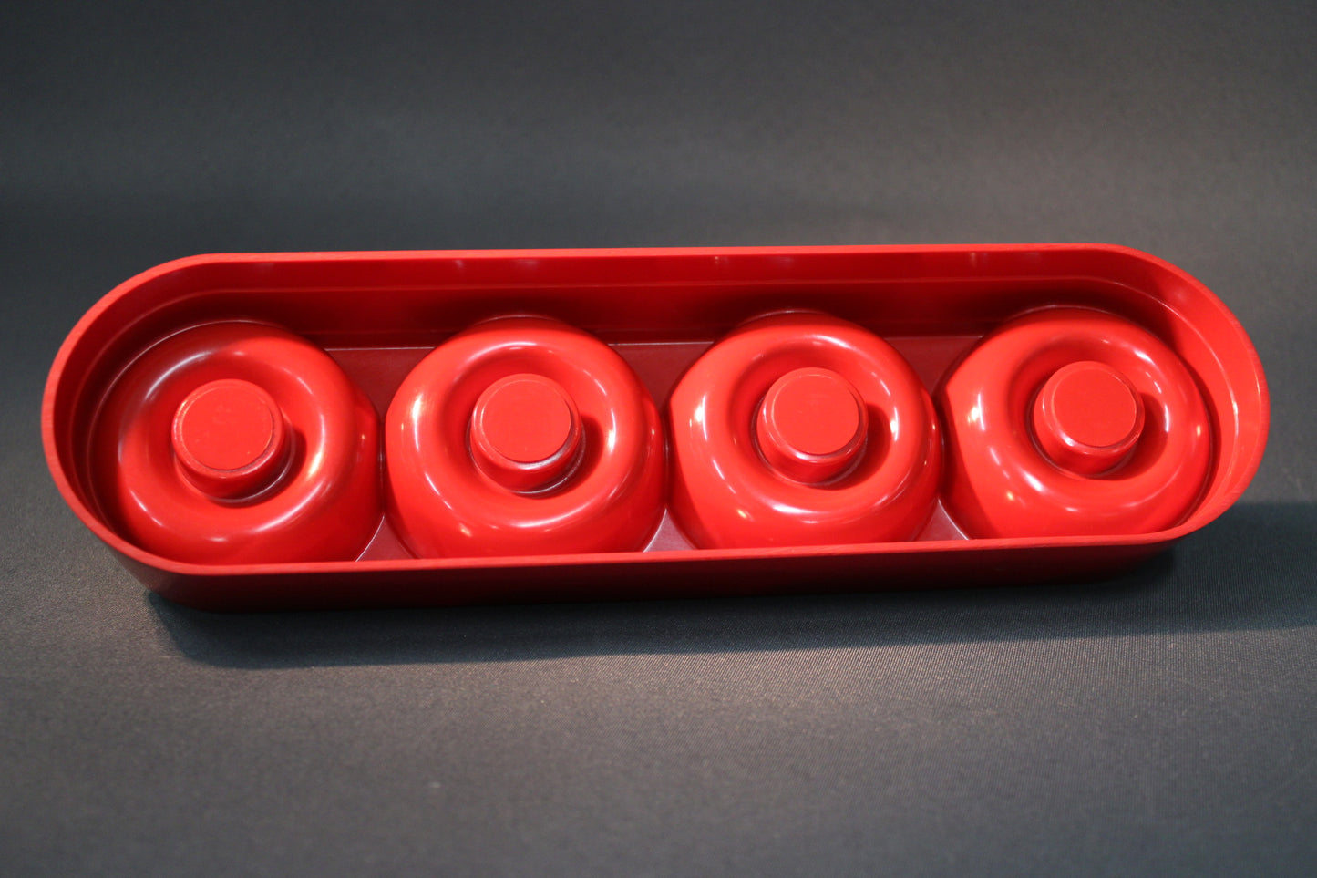 Punainen muovinen retro kynttilänjalka, pohjan muotoilu ja neljä kynttiläpesää